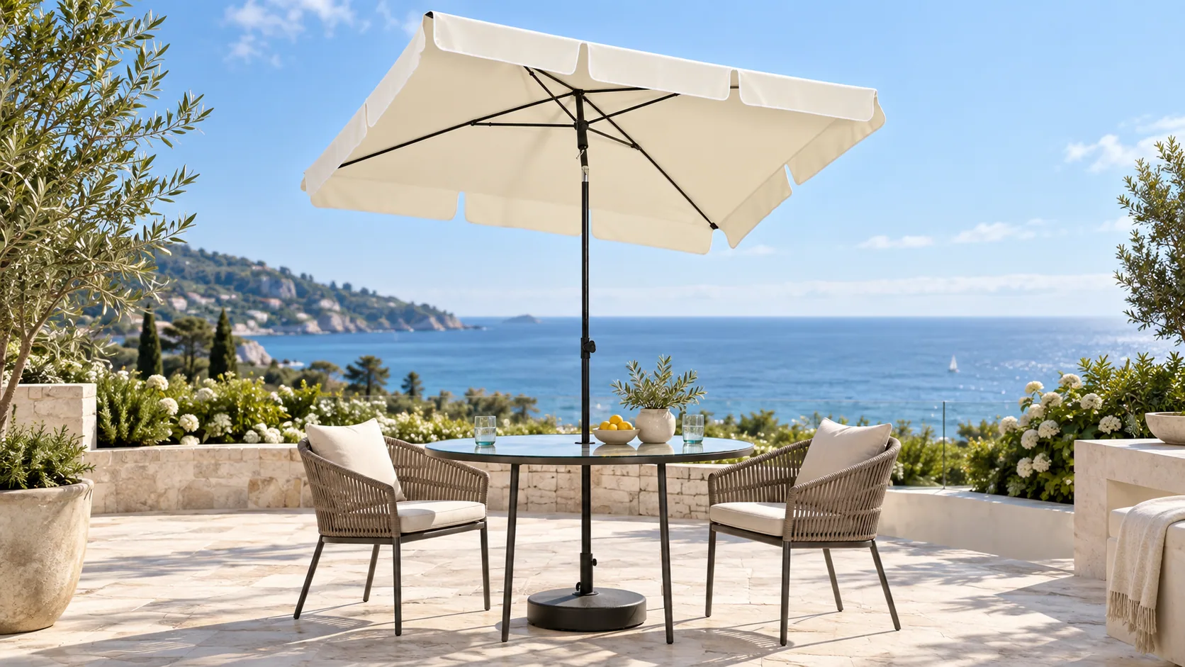 Ivory rectangular umbrella shading a table and woven chairs on a sunny coastal terrace
