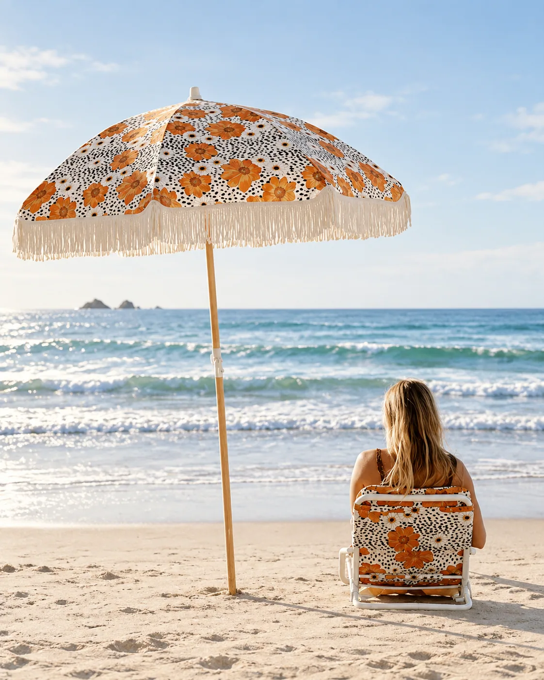 Orange floral fringe parasol and matching chair beside the sea