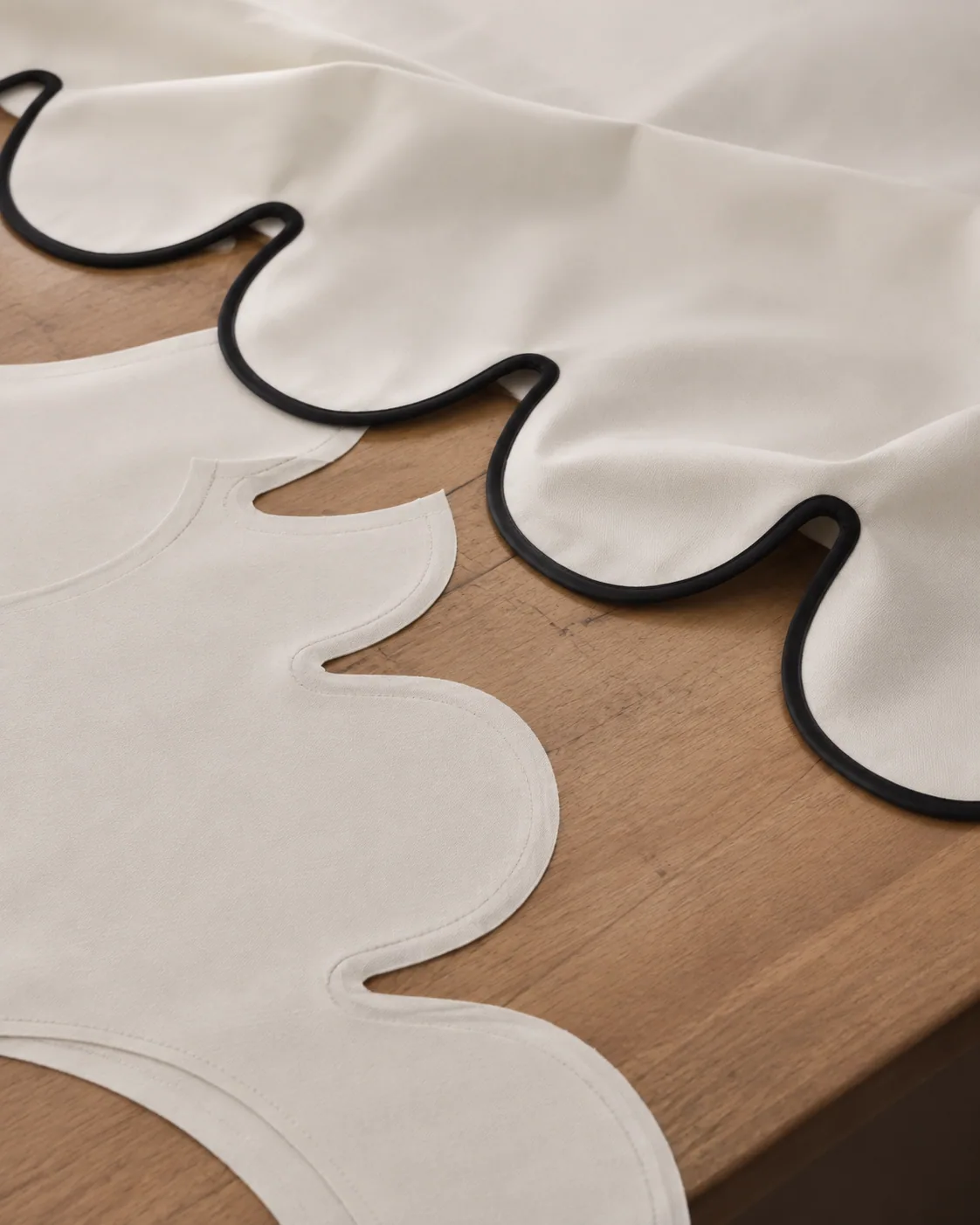 Scalloped ivory fabric cutting and black piping detail study