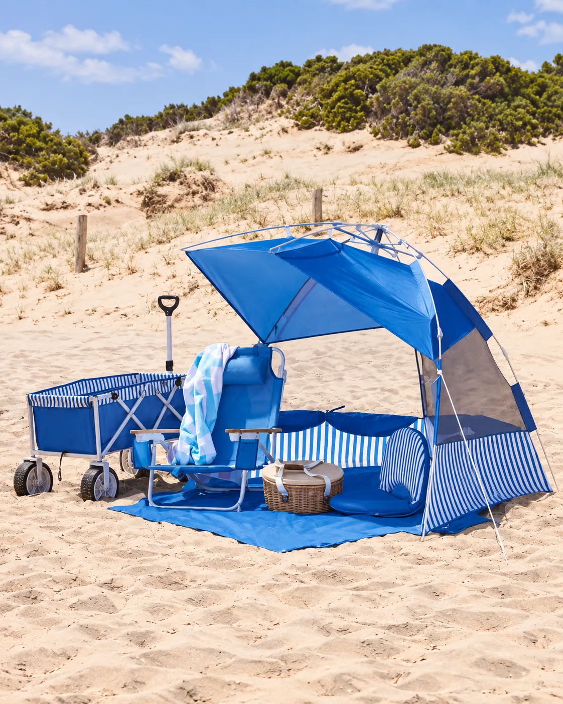 Blue beach chairs, striped wagon and matching sun shelter on coastal sand dunes