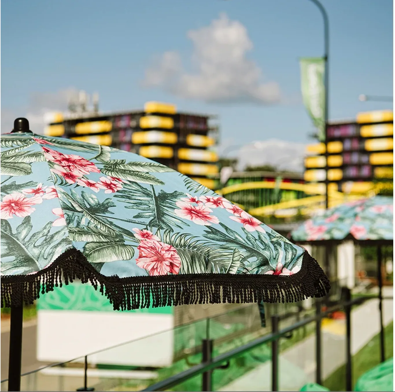 Tropical floral beach umbrella with black fringe in an outdoor setting