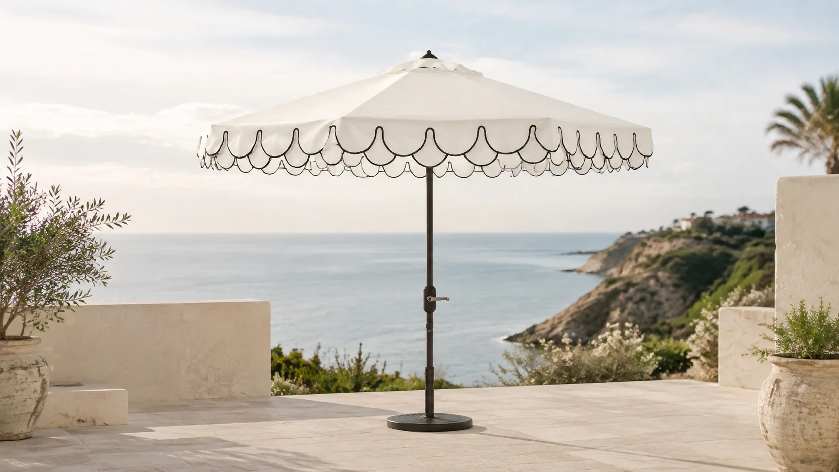 Ivory scalloped umbrella with black piping and a side crank on a coastal terrace