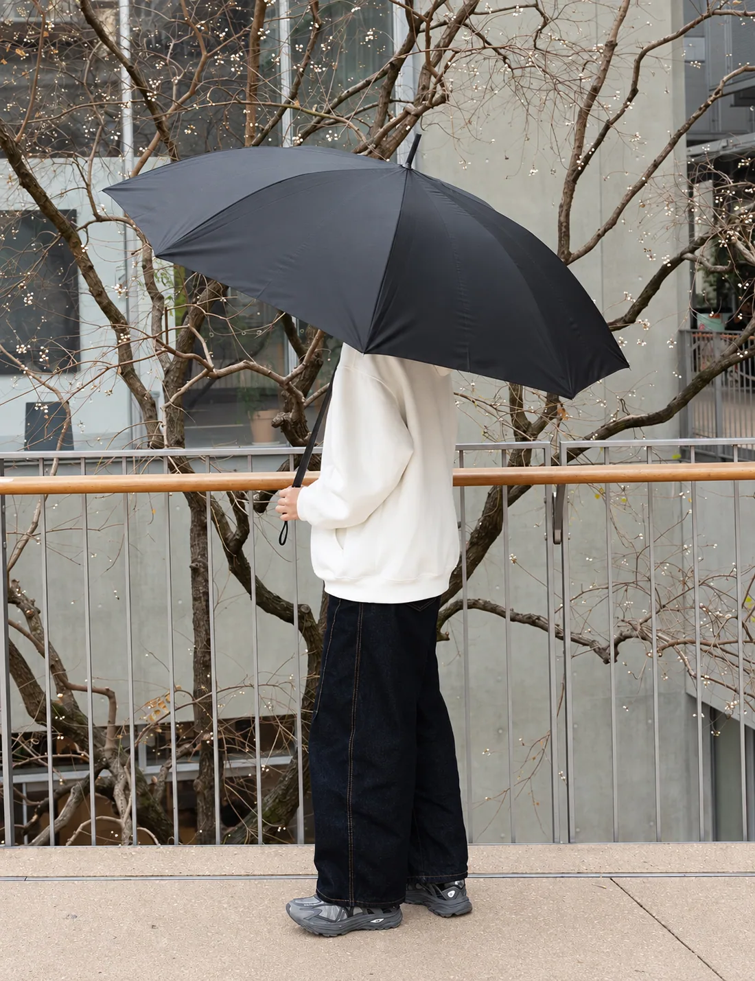 Open black carbon-fibre umbrella beside an urban terrace