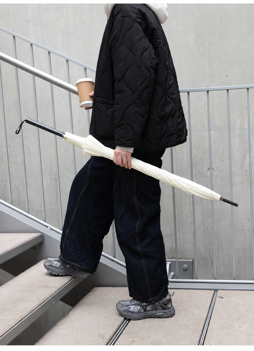 Closed ivory carbon-fibre umbrella carried on a stairway
